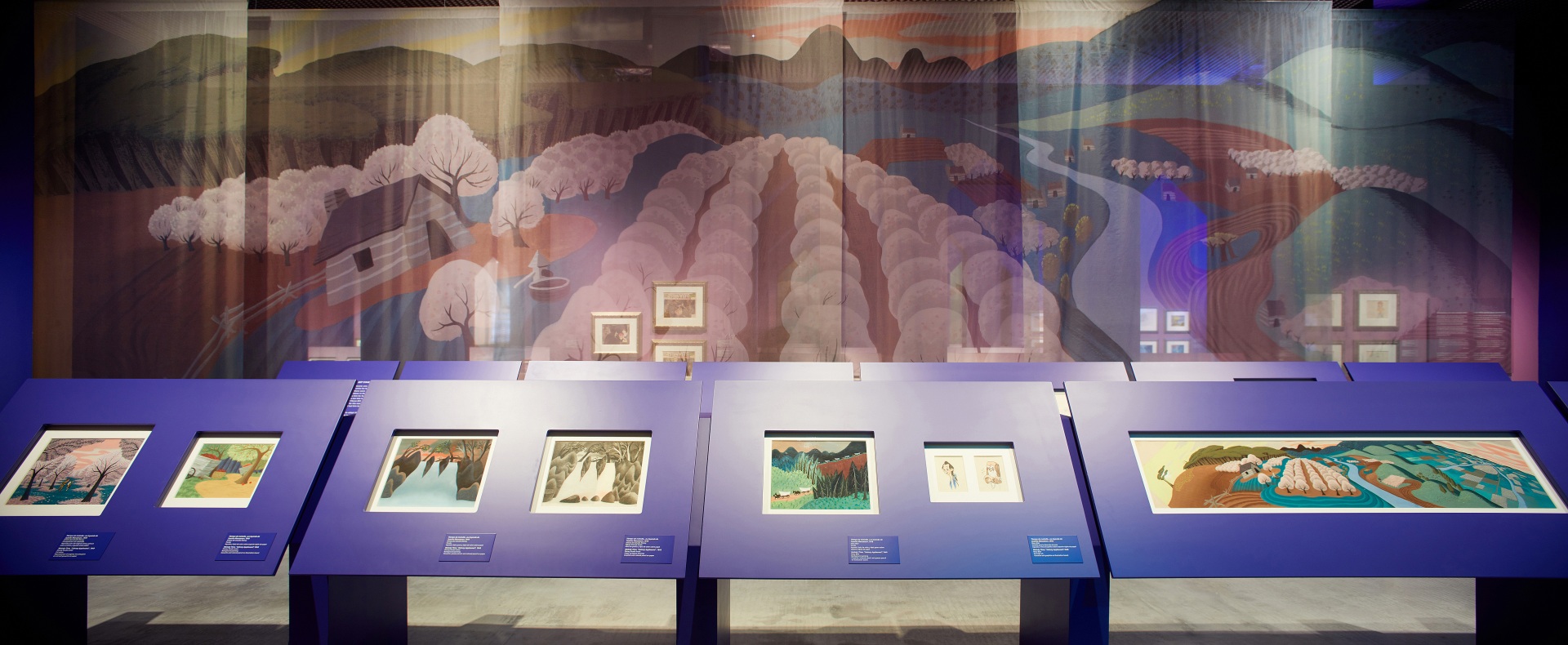 Exposición sobre Walt Disney. Mesas de dibujo color morado. Paisaje de colores de fondo.  